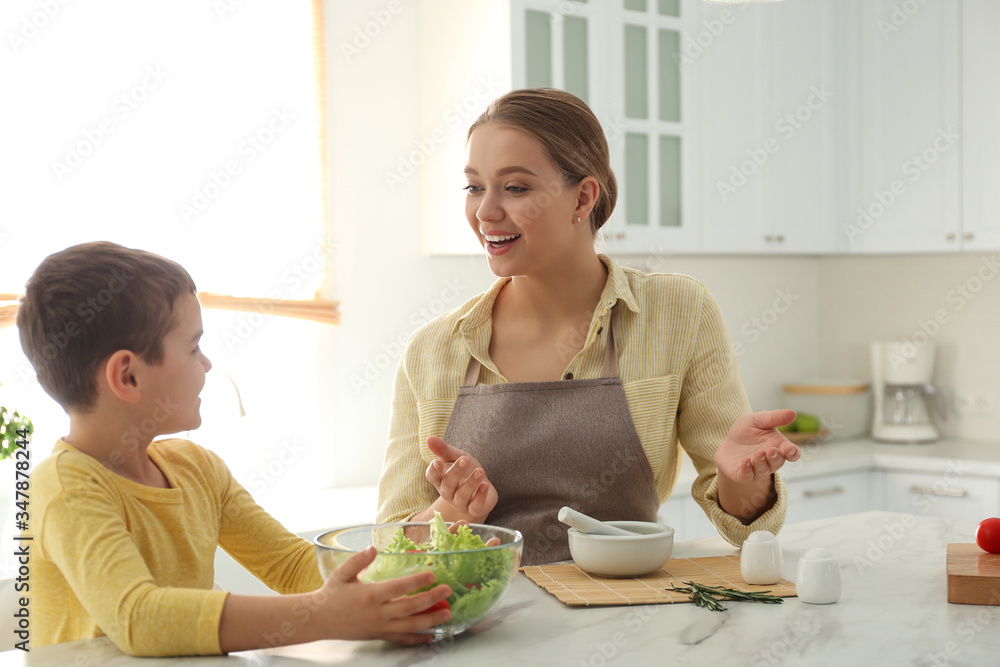 Wall mural Mother and son cooking salad together in kitchen