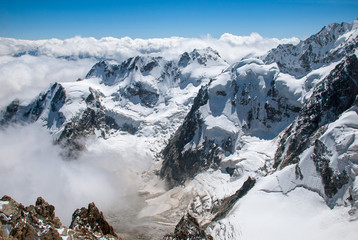 Alpine landscape with rocky peaks covered with snow and clouds