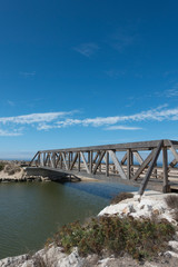 wooden bridge crossing a small river linking a path to a boardwalk. Praia da Areia Branca, near Lourinha, Portugal