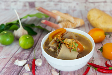 Oxtail soup in a bowl and spices placed on a wooden floor