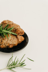 Cozy wheat croissants with sesame seeds in a dark plate isolated on white. Organic food concept.
