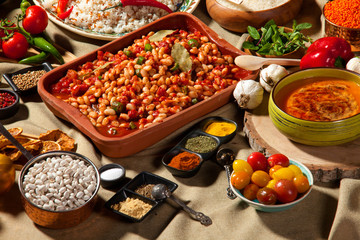 cooked and uncooked haricot beans, served with traditional cooked rice and Traditional red lentil soup. Table garnished with legumes, vegetables and seasonings. Rich cuisine, delicious food.