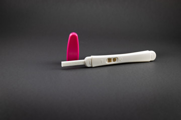 Positive pregnancy test in white and rose tones. Vertical stripes for positive in black background with copy space. 