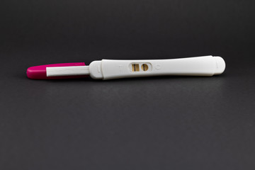 Positive pregnancy test in white and rose tones. Vertical stripes for positive in black background with copy space. 