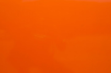 Orange painted lacquered metal surface closeup as orange background