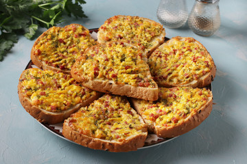 Hot sandwiches with cheese and sausage in a plate on light blue background, Horizontal format, Closeup, selective focus