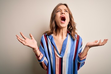 Young blonde girl wearing colorful striped shirt over isolated background crazy and mad shouting...
