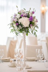Wedding table decorated on mauve color. Centerpiece full of violet flowers in the middle