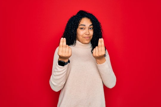 Young african american curly woman wearing casual turtleneck sweater over red background doing money gesture with hands, asking for salary payment, millionaire business