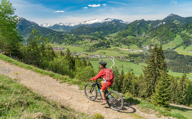 Naklejka premium pretty senior woman riding her electric mountain bike on the Wallraff Trail in the Nebelhorn area above Oberstdorf, Allgau Alps, Bavaria, 
