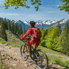 Fototapeta premium pretty senior woman riding her electric mountain bike on the Wallraff Trail in the Nebelhorn area above Oberstdorf, Allgau Alps, Bavaria, 