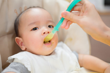 Asian baby boy eating blend food on a high chair, Mother  Feeds A Little Baby With A Spoonful Of Food ,eating  first time at home