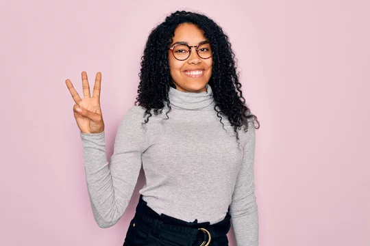 Young african american woman wearing turtleneck sweater and glasses over  pink background showing and pointing up with fingers number three while  smiling confident and happy. Stock Photo | Adobe Stock