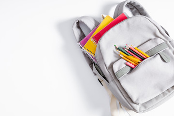 Fototapeta Back to school concept. Backpack with school supplies, pens, pencils, notebook on white background. Flat lay, top view, copy space obraz