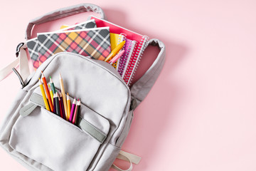 Back to school concept. Backpack with school supplies, pens, pencils, notebook on pastel pink background. Flat lay, top view, copy space - obrazy, fototapety, plakaty