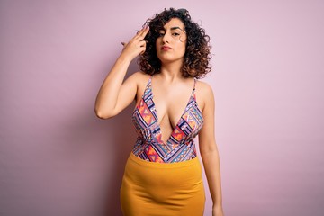 Young beautiful arab woman on vacation wearing swimsuit and sunglasses over pink background Shooting and killing oneself pointing hand and fingers to head like gun, suicide gesture.