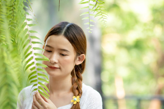 Defocused and blurred image for background. An Asian woman feels standing under a tree. Look at the leaves with sad eyes. Loneliness alone. coye space. bokeh green.