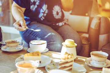 Happiness female friends meeting and drinking tea or coffee with cakes together at cafe in the afternoon. People, leisure and communication concept. Selective focus.
