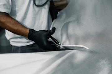 Manufacturing process of a surfboard by a white shirt shaper and black gloves inside his workshop....
