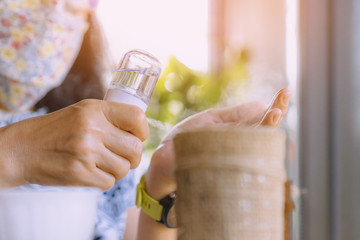 Woman using alcohol nano mist sprayer antiseptic cleaning on her hands protection during...