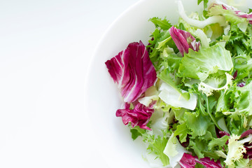 Fresh salad in a white plate isolated at white background. Top view.