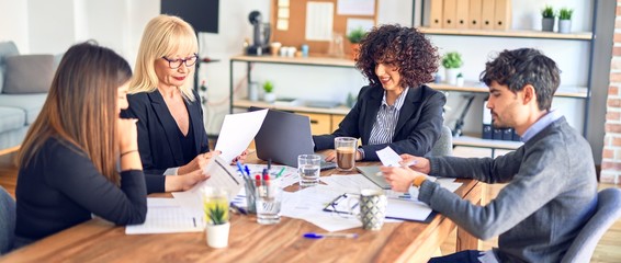 Group of business workers smiling happy and confident. Working together with smile on face  using laptop and speaking at the office