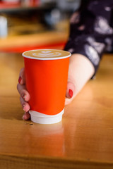 Female's hand gives paper cup with coffee
