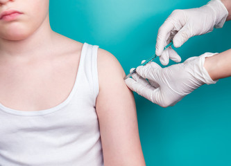 Doctor uses a syringe to vaccinate child. Inoculation in the shoulde