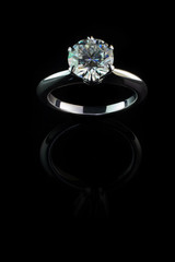 Jewelry, golden ring with a diamond on a black background, reflection from a shiny surface