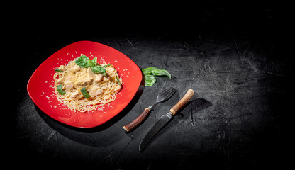 Tasty appetizing classic italian spaghetti pasta with chicken, cheese on dark background