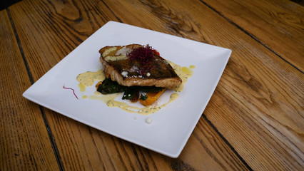 Delicious fried salmon fillet, seasonings on blue rustic concrete table. Cooked salmon steak with pepper, herbs, lemon, garlic, olive oil, spoon. Grilled fresh fish. Fish for healthy dinner. Close-up