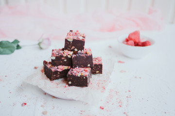 Homemade chocolate fudge with strawberries and pine nuts