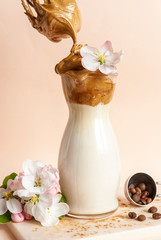  Trendy whipped cold dalgona coffee in glass and mixer whisk with apple tree flowers