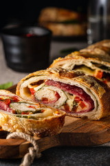 Traditional Italian Stromboli stuffed with cheese, salami, red pepper and spinach. Photo in a dark...