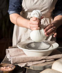 Preparation of cottage cheese - woman straining the milk through a cheesecloth