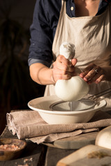 Fototapeta na wymiar Preparation of cottage cheese - woman straining the milk through a cheesecloth