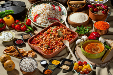 cooked and uncooked haricot beans, served with traditional cooked rice and Traditional red lentil soup. Table garnished with legumes, vegetables and seasonings. Rich cuisine, delicious food.