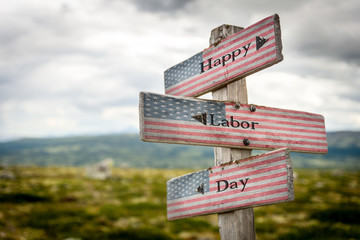 Happy labor day text on wooden american flag signpost outdoors in nature.