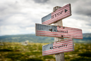 stop animal cruelty text on wooden american flag signpost outdoors in nature.