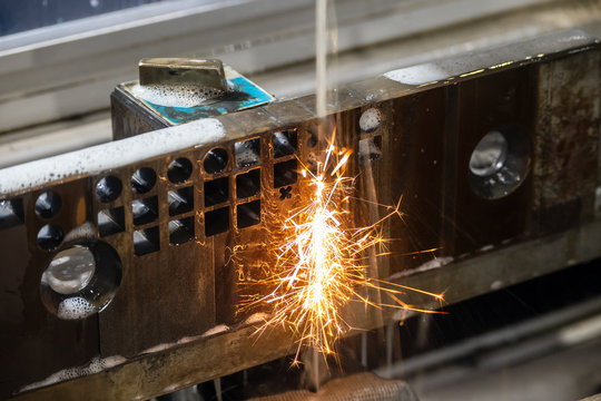 The wire-EDM machine cutting the die parts with the sparking light. The mould and die manufacturing process by wirecut machine control by CNC program.