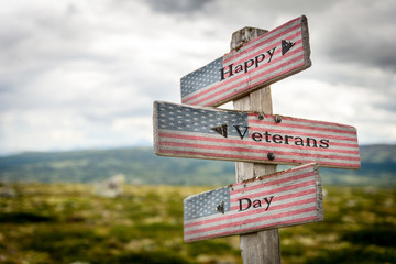 happy veterans day  text on wooden american flag signpost outdoors in nature.
