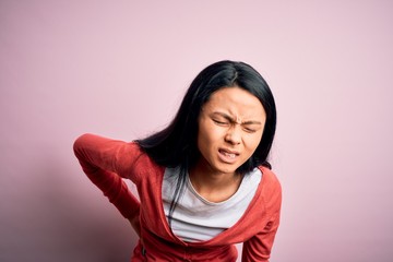 Young beautiful chinese woman wearing casual sweater over isolated pink background Suffering of backache, touching back with hand, muscular pain
