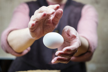 Hands of a woman perform a magic trick with the egg. Levitation of the egg in the air