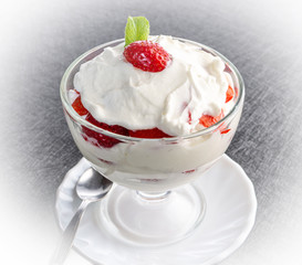 Strawberries with whipped cream in a glass bowl on dark background - 347900469