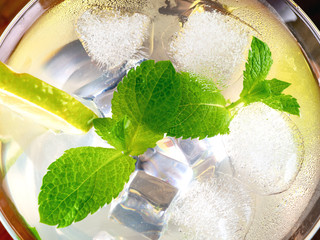 Glass with mojitos and lemon wedges and mint on a tray - 347900494