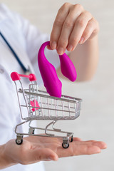 The faceless gynecologist recommends buying a clitoral vaginal vibrator to maintain women's health. The doctor holds a mini trolley and a masturbator for vivid orgasms.