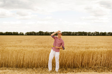 Naklejka na ściany i meble Young handsome happy man standing in wheat field 