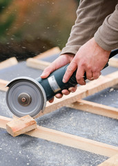 construction worker on a renovation roof covering it with tiles using hammer, crane and grinder