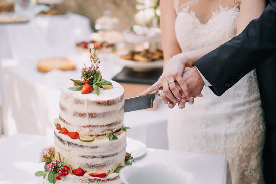 photo of a bride and a groom cutting a strawberry wedding cake