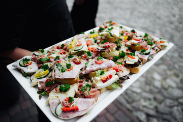 photo of a waiter serving cold meat on small bread bites